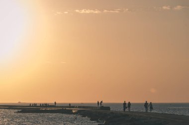 dalgakıran deniz günbatımı insanlar tarafından - vintage bir retro görünüm ile sonunda kırmızı deniz feneri ile