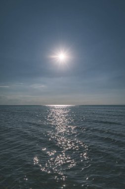 arkadan aydınlatmalı mavi gökyüzü altında sakin deniz üzerinde gündoğumu