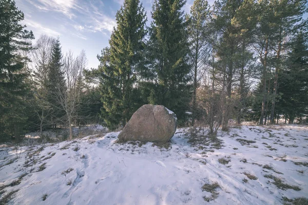 large granite rock on snow covered ground in nature