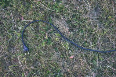 yeşil çimenlerin üzerinde Döşeme siyah elektrik tel 