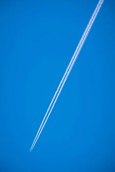 平面と青い空に白い煙のトレイル — ストック写真