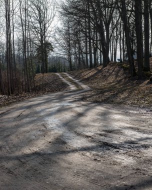 boş ülke stabilize yol çamur ile su birikintileri ve darbelere. kirli yol yüzeyi kum ve küçük taşlarla