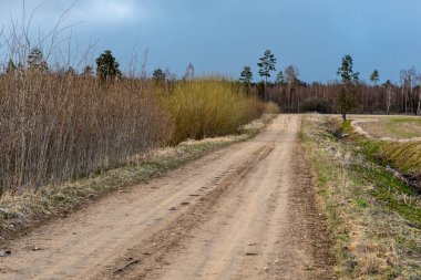boş ülke stabilize yol çamur ile su birikintileri ve darbelere. kirli yol yüzeyi kum ve küçük taşlarla
