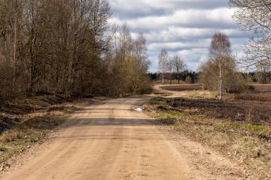 boş ülke stabilize yol çamur ile su birikintileri ve darbelere. kirli yol yüzeyi kum ve küçük taşlarla
