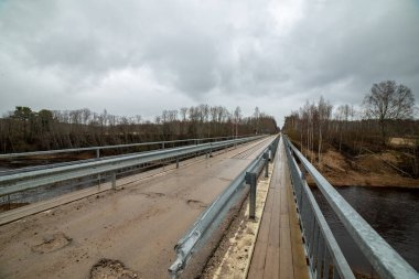 boş ülke stabilize yol çamur ile su birikintileri ve darbelere. kirli yol yüzeyi kum ve küçük taşlarla