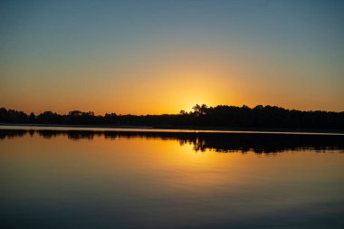 Hava günbatımı sakin su ve su sessiz simmetry ve ağaç yansımalar ile ülke göl kenarında sakin