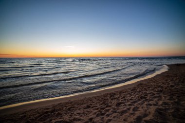 temiz gökyüzü ve sakin su ile yaz aylarında renkli günbatımı deniz sahilde. Baltık Denizi