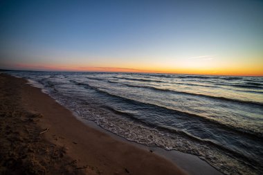 temiz gökyüzü ve sakin su ile yaz aylarında renkli günbatımı deniz sahilde. Baltık Denizi