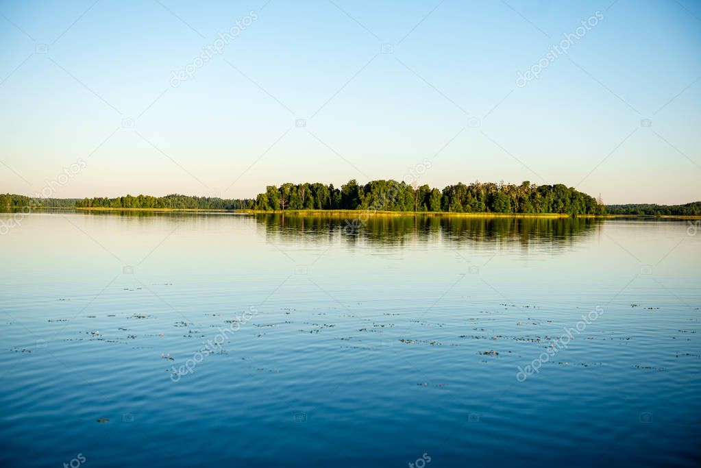 calm weather sunset on country lake with calm water and silent simmetry and tree reflections on water