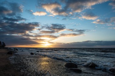 Deniz plaj kayalar ve fırtınalı su üzerinde dramatik günbatımı