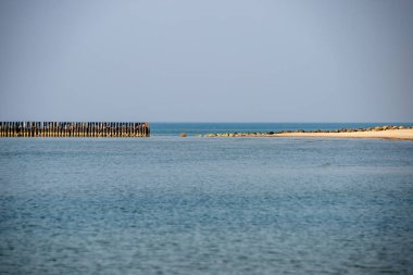 Sakin deniz plaj yaz büyük kayalar ve ahşap direklerin 