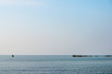 Sakin deniz plaj yaz büyük kayalar ve ahşap direklerin 