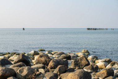 Sakin deniz plaj yaz büyük kayalar ve ahşap direklerin 