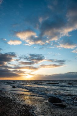 Deniz plaj kayalar ve fırtınalı su üzerinde dramatik günbatımı