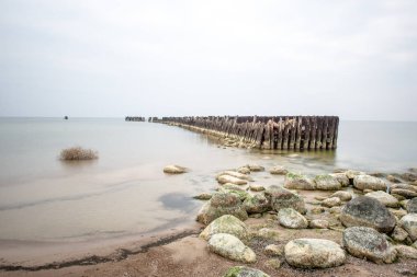 Sakin deniz plaj yaz büyük kayalar ve ahşap direklerin 