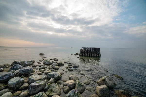 Spokojne morze plaża w lecie z dużych skał i drewnianych słupach z — Zdjęcie stockowe