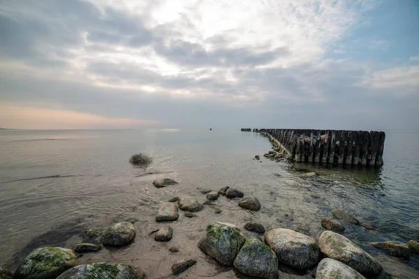 Playa de mar tranquilo en verano con grandes rocas y postes de madera de — Foto de Stock