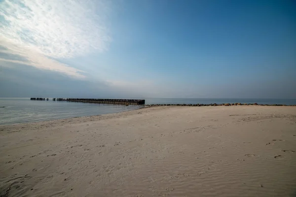 Nyáron a nagy sziklák és fa oszlopok a nyugodt tenger beach — Stock Fotó