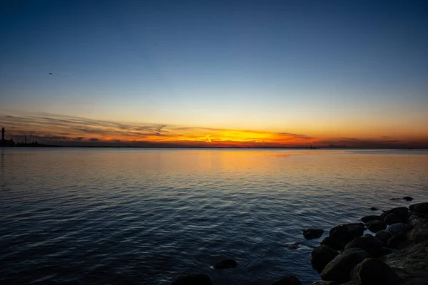Dramático pôr do sol sobre a praia do mar com rochas e água tempestuosa — Fotografia de Stock