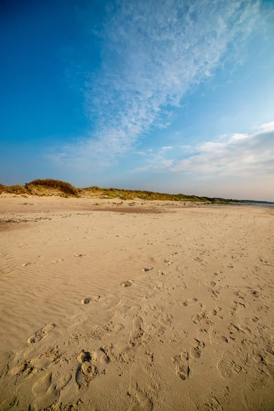 Calm sea beach in summer with large rocks and wooden poles from Stock Picture