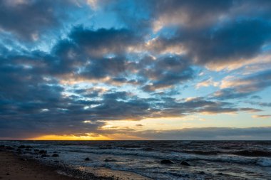 Letonya kayalık deniz kıyısı ile sahilde fırtına hava. yüksek dalgalar ile kayalar üzerinde günbatımı
