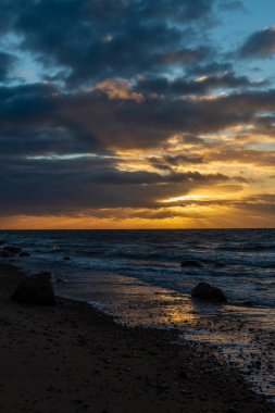 Letonya kayalık deniz kıyısı ile sahilde fırtına hava. yüksek dalgalar ile kayalar üzerinde günbatımı