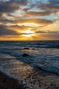 Letonya kayalık deniz kıyısı ile sahilde fırtına hava. yüksek dalgalar ile kayalar üzerinde günbatımı