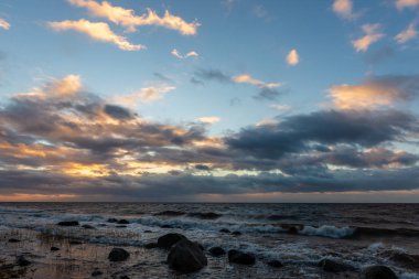 Letonya kayalık deniz kıyısı ile sahilde fırtına hava. yüksek dalgalar ile kayalar üzerinde günbatımı