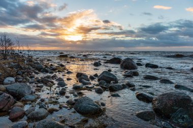 Letonya kayalık deniz kıyısı ile sahilde fırtına hava. yüksek dalgalar ile kayalar üzerinde günbatımı
