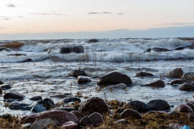 Letonya kayalık deniz kıyısı ile sahilde fırtına hava. yüksek dalgalar ile kayalar üzerinde günbatımı