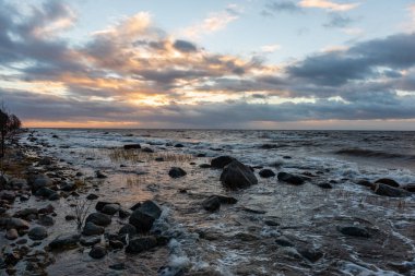 Letonya kayalık deniz kıyısı ile sahilde fırtına hava. yüksek dalgalar ile kayalar üzerinde günbatımı