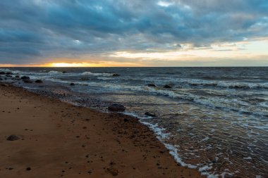 Letonya kayalık deniz kıyısı ile sahilde fırtına hava. yüksek dalgalar ile kayalar üzerinde günbatımı