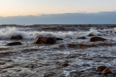 Letonya kayalık deniz kıyısı ile sahilde fırtına hava. yüksek dalgalar ile kayalar üzerinde günbatımı