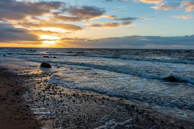 Letonya kayalık deniz kıyısı ile sahilde fırtına hava. yüksek dalgalar ile kayalar üzerinde günbatımı