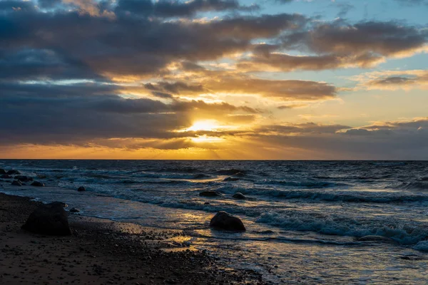 Letonya kayalık deniz kıyısı ile sahilde fırtına hava. yüksek dalgalar ile kayalar üzerinde günbatımı