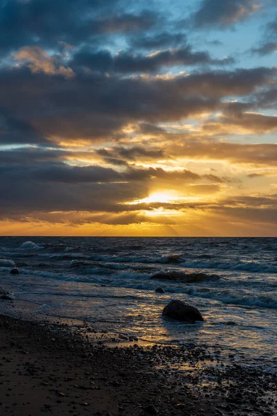 Letonya kayalık deniz kıyısı ile sahilde fırtına hava. yüksek dalgalar ile kayalar üzerinde günbatımı
