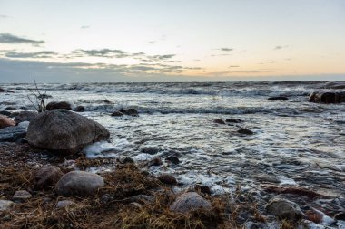 Letonya kayalık deniz kıyısı ile sahilde fırtına hava. yüksek dalgalar ile kayalar üzerinde günbatımı