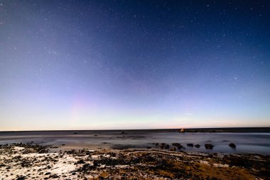 Kış aylarında deniz Plajı üzerinde karanlık gece Aurora Borealis ve yıldızlar. Kuzey ışıkları