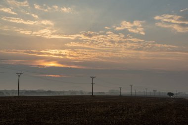 sonbaharda Slovakça manzara üzerinde bulutlu ve sisli gündoğumu. Tatra güneş doğar gibi arka planda moountains. Elektrik direkleri alanında