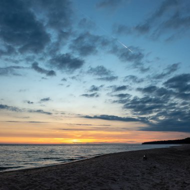 koyu mavi su ve dramatik kontrastlı bulutlar ile sakin deniz Plajı üzerinde renkli günbatımı. suda kayalar