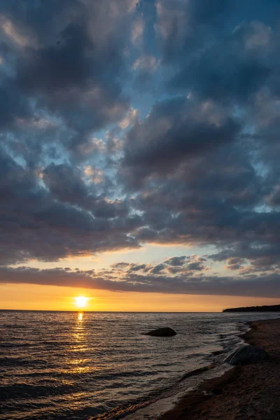 五颜六色的日落在平静的海滩与深蓝色的水和戏剧性的对比云 水中的岩石 — 图库照片