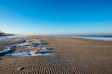 düşük kar kapsama ile kışın dondurulmuş deniz Plajı. Sahilde güneşli bir gün içinde buz