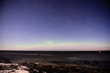 Kış aylarında deniz Plajı üzerinde karanlık gece Aurora Borealis ve yıldızlar. Kuzey ışıkları