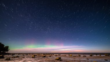 Kış aylarında deniz Plajı üzerinde karanlık gece Aurora Borealis ve yıldızlar. Kuzey ışıkları