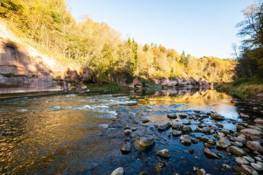 kıyılarda kumtaşı kayalıklar ile orman nehri üzerinde güzel altın gündoğumu. fırtınalı su