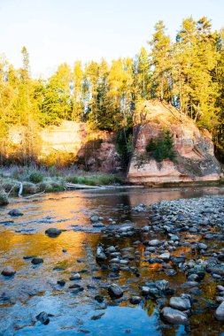 kıyılarda kumtaşı kayalıklar ile orman nehri üzerinde güzel altın gündoğumu. fırtınalı su