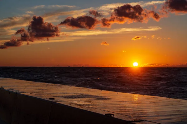 dark red sunset over sea in evening with broken clouds