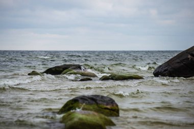 ıslak kum büyük kayalar ile fırtınalı deniz plajı. Baltık denizi