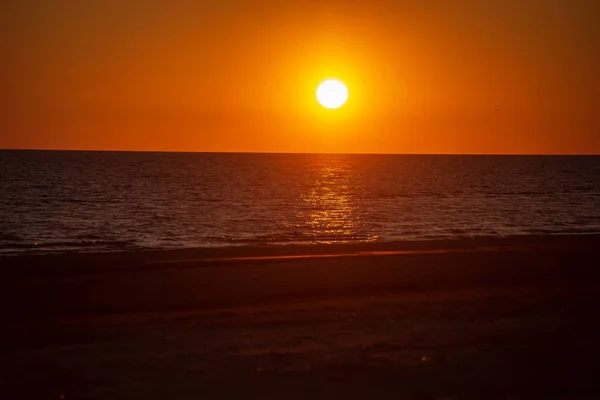 dark red sunset over sea in evening with broken clouds