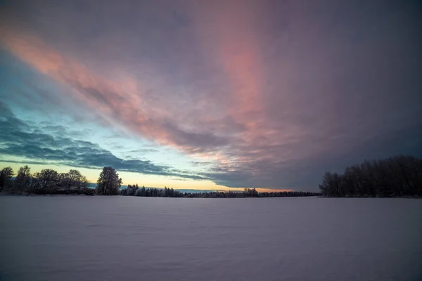 田舎の冬の雪のフィールド上のカラフルな夕日の光 — ストック写真